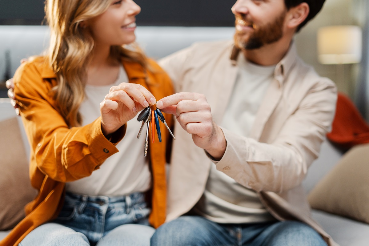 Happy family holding keys from new home. Smiling man and woman hugging buying new property